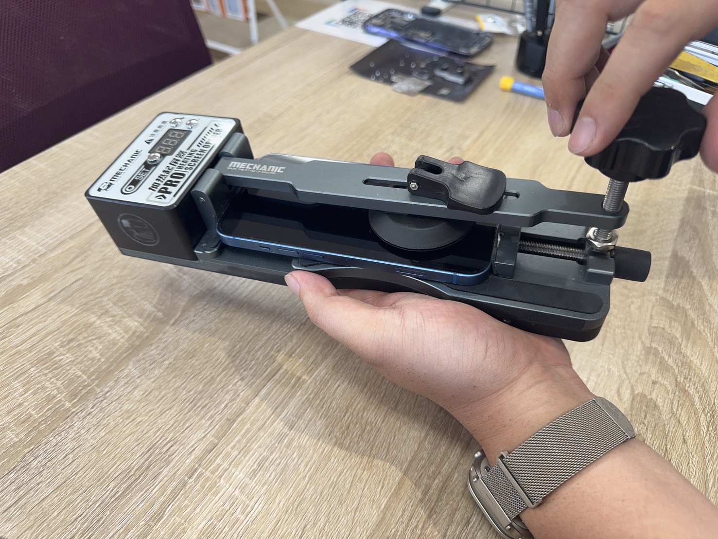 専用の機械でiPhoneの画面を開口する作業(イケモバ宮古島店)